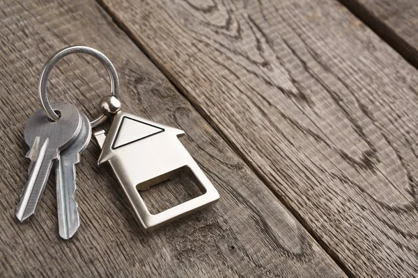 Schlüsselbund mit Schlüsselanhänger in Hausform auf rustikalem Holz — Stockfoto
