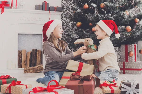 Enfants heureux dans chapeaux de Père Noël déballer cadeaux de Noël — Photo