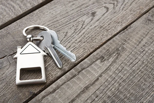 Schlüsselbund mit Schlüsselanhänger in Hausform auf rustikalem Holz — Stockfoto