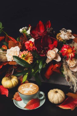 Siyah arka plan üzerine cappuccino kahve ve çiçek kompozisyon