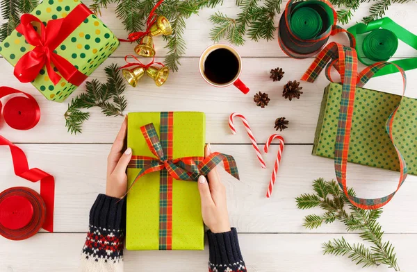 Weibliche Hände verpacken Weihnachtsgeschenke auf unordentlichem Tischhintergrund — Stockfoto