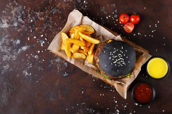 Black bun burger with potato wedges top view — Stock Photo, Image