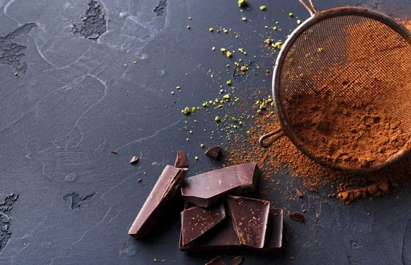Cocoa powder in a sieve over black slate background — Stock Photo, Image