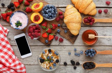 Sabah yemek ve rustik ahşap masa üstünde smartphone