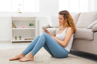 Kanepenin üzerinde cep telefonu kullanan genç kız