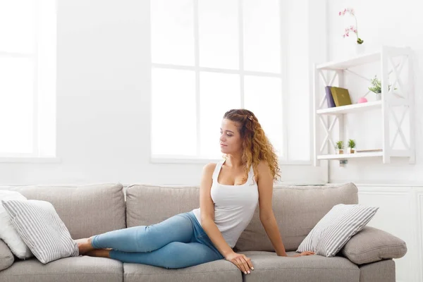 Junge rothaarige Frau denkt auf beiger Couch — Stockfoto