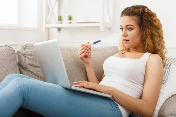 Donna che naviga su laptop con test di gravidanza — Foto Stock