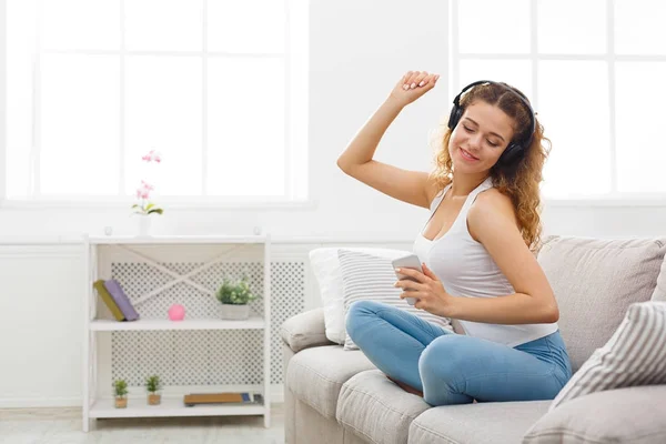 Happy young woman in headphones on beige couch — Stock Photo, Image