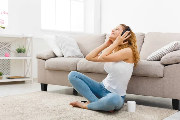 Gelukkig jonge vrouw in de koptelefoon op vloer — Stockfoto