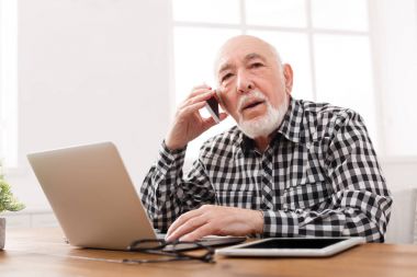 Dizüstü bilgisayar ile telefonda konuşan üst düzey adam