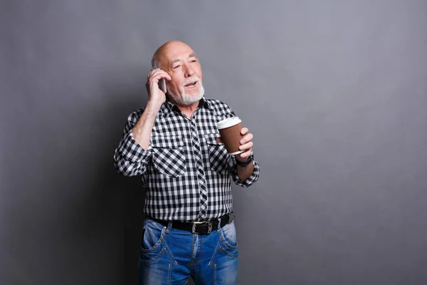 Homem idoso ocupado falando ao telefone, bebendo café — Fotografia de Stock