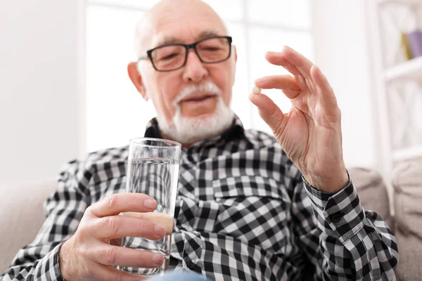 Velho tomando um copo de água e pílulas na mão — Fotografia de Stock