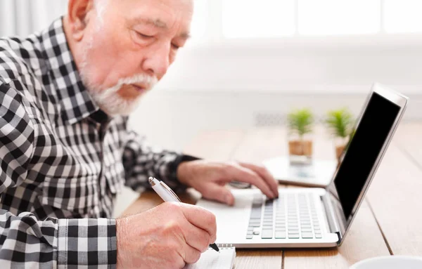 Ώριμος άνδρας χρησιμοποιώντας φορητό υπολογιστή και γράφοντας στο Σημειωματάριο (Notepad) — Φωτογραφία Αρχείου