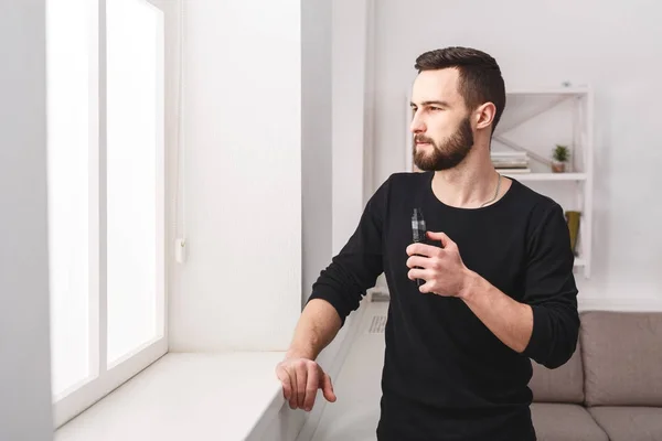 Vaping e-sigara pencerede evde genç adam — Stok fotoğraf