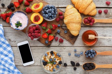 Sabah yemek ve rustik ahşap masa üstünde smartphone