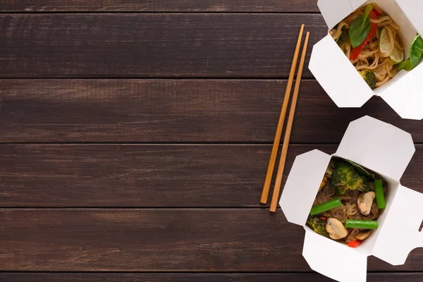 Asiatisches Essen in Lieferbox auf Holzboden — Stockfoto