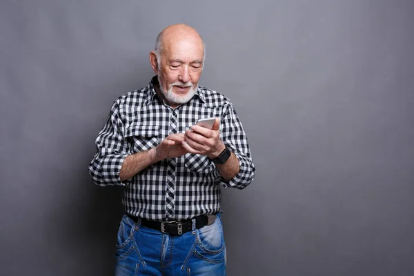 Alegre sênior homem digitando mensagem no smartphone — Fotografia de Stock