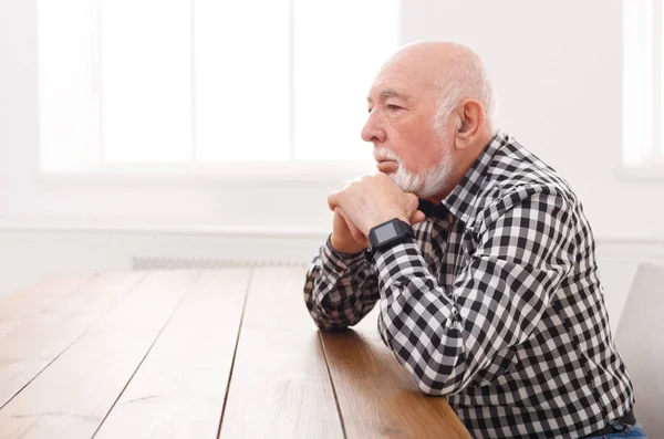 Pensivo homem idoso sentado à mesa, espaço de cópia — Fotografia de Stock