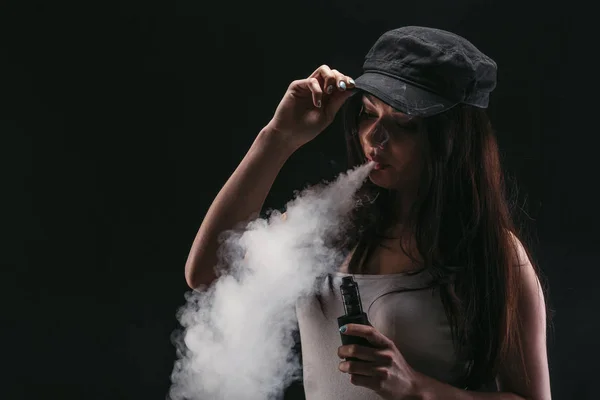 Mujer joven vapeando e-cigarrillo con humo en negro — Foto de Stock