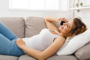 Genç kız bej kanepe mobil yalan konuşuyor