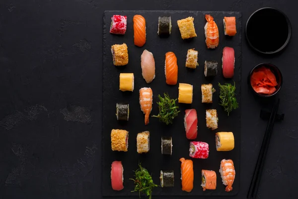 Sushi, maki och rullar på svart bakgrund — Stockfoto