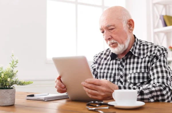 Senior liest Nachrichten auf digitalem Tablet — Stockfoto