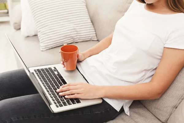 Ragazza irriconoscibile con computer portatile seduto sul divano — Foto Stock