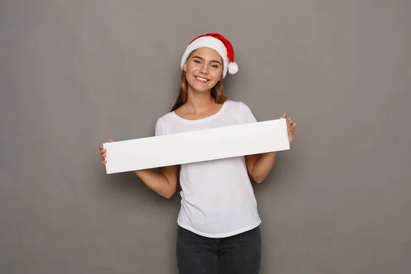Mladá žena v santa hat drží prázdný bílý nápis — Stock fotografie