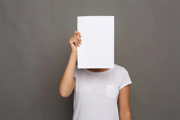 Young woman with blank white paper at face