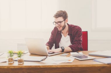 Genç modern beyaz ofiste dizüstü kullanarak iş adamı memnun