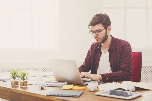 Joven hombre de negocios que trabaja con el ordenador portátil en la oficina blanca moderna — Foto de Stock