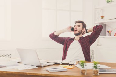 Genç rahat işadamı bir telefon konuşma modern beyaz ofiste vardır.