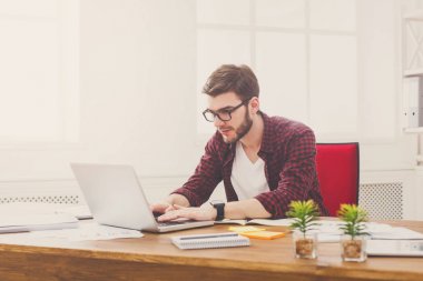 Modern beyaz ofis içinde laptop ile çalışan dalgın genç işadamı