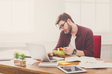 Meşgul genç adam iş yemeği modern ofis iç vardır.