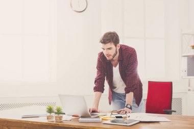 Genç işadamı tarafından modern beyaz ofis içinde belgili tanımlık laptop ayakta