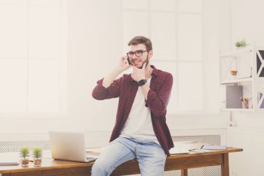 Konsantre genç işadamı modern beyaz ofiste bir telefon konuşma vardır