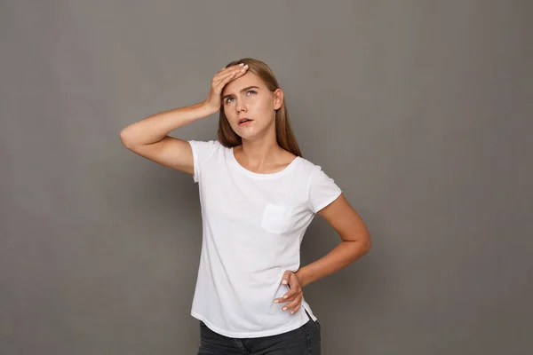 Mujer concentrada pensando en fondo gris — Foto de Stock