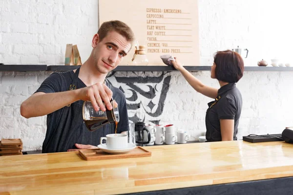 Bartenders masculinos e femininos preparando café fresco no interior do café — Fotografia de Stock