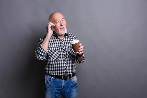 Homem idoso ocupado falando ao telefone, bebendo café — Fotografia de Stock