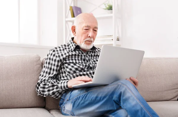 Pensativo homem sênior lendo notícias no laptop — Fotografia de Stock