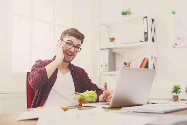 Upptagen ung man har affärslunch i moderna kontor interiör — Stockfoto