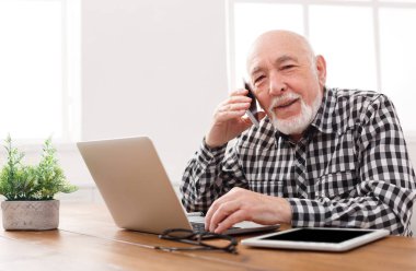 Dizüstü bilgisayar ile telefonda konuşan üst düzey adam