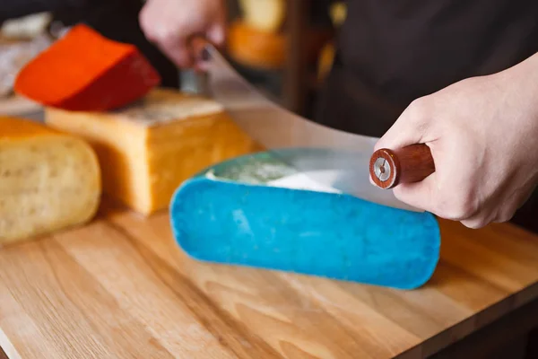 Cutting gouda pesto blue cheese in grocery shop — Stock Photo, Image