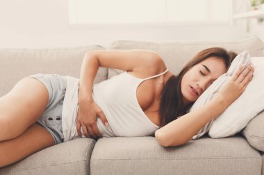 Genç kız kanepede uzanmış mide ağrısı muzdarip