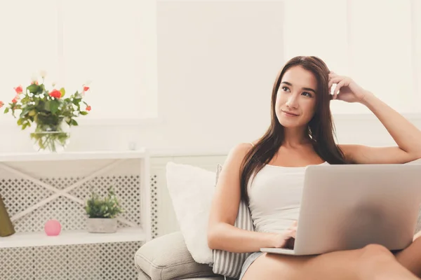 Giovani donne che utilizzano il computer portatile seduto sul divano in soggiorno bianco — Foto Stock