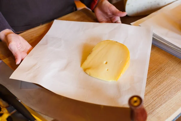 Помощница продавщицы упаковывает кусок сыра — стоковое фото