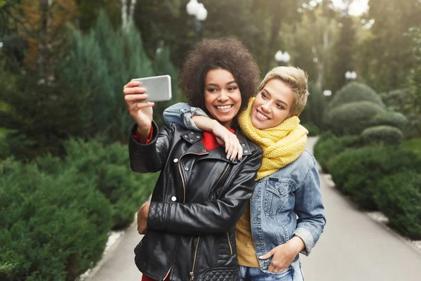 Happy girls with smartphone outdoors in the park — Stock Photo, Image