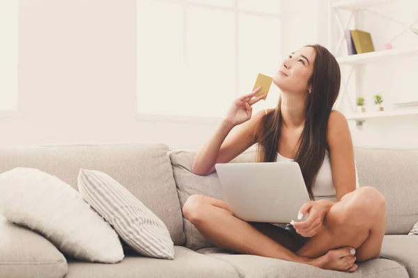 Düşünceli genç kız kanepede oturan online alışveriş — Stok fotoğraf