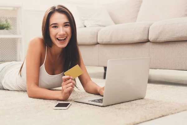 Happy young girl shopping online on floor