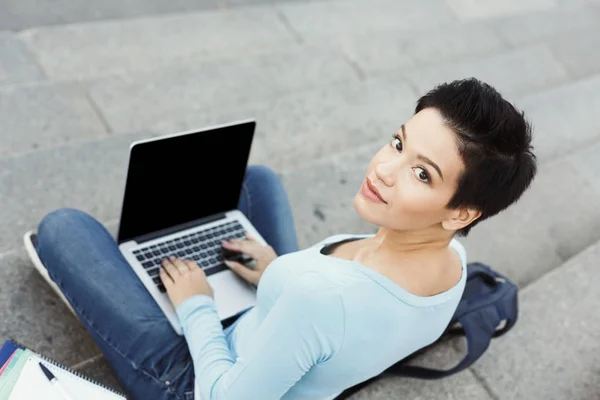 ノート パソコンを屋外で使う若い女性を笑顔 — ストック写真